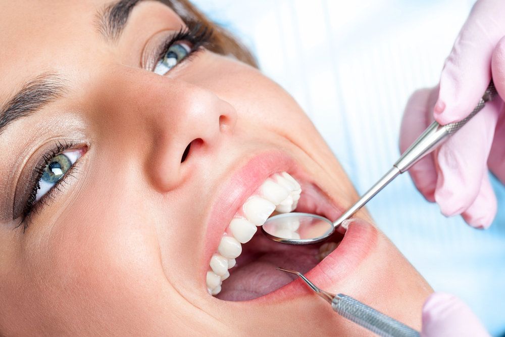 Attractive woman with dental exam tools next to her teeth